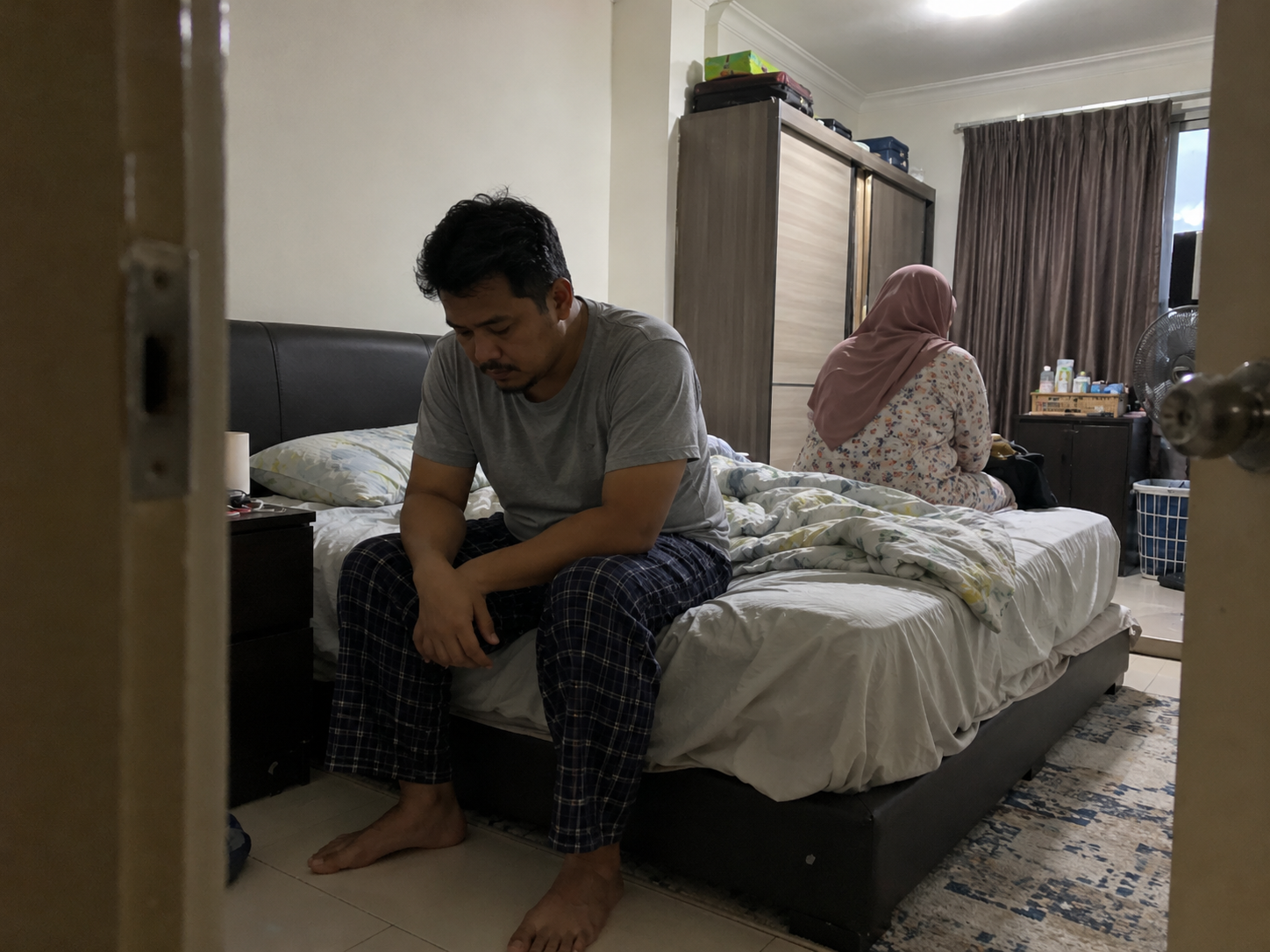 Pasangan duduk berjauhan di bilik tidur